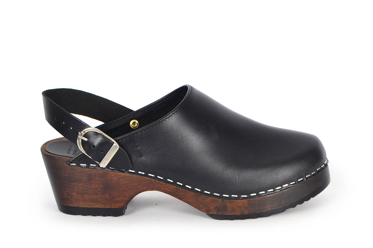 Sonoma clogs in black pull up leather on a brown wooden bottom