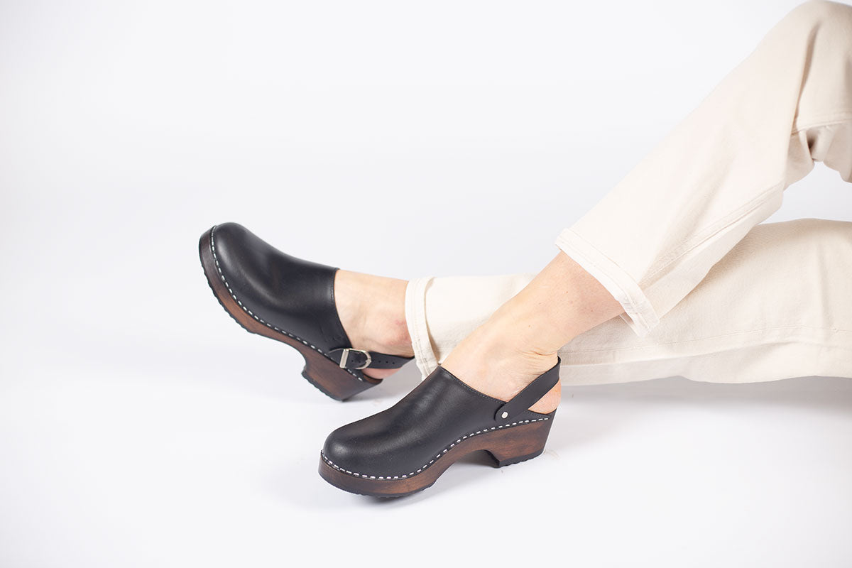 Sonoma clogs in black pull up leather on a brown wooden bottom